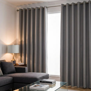 Grey blockout curtains hanging in a modern bedroom blocking sunlight