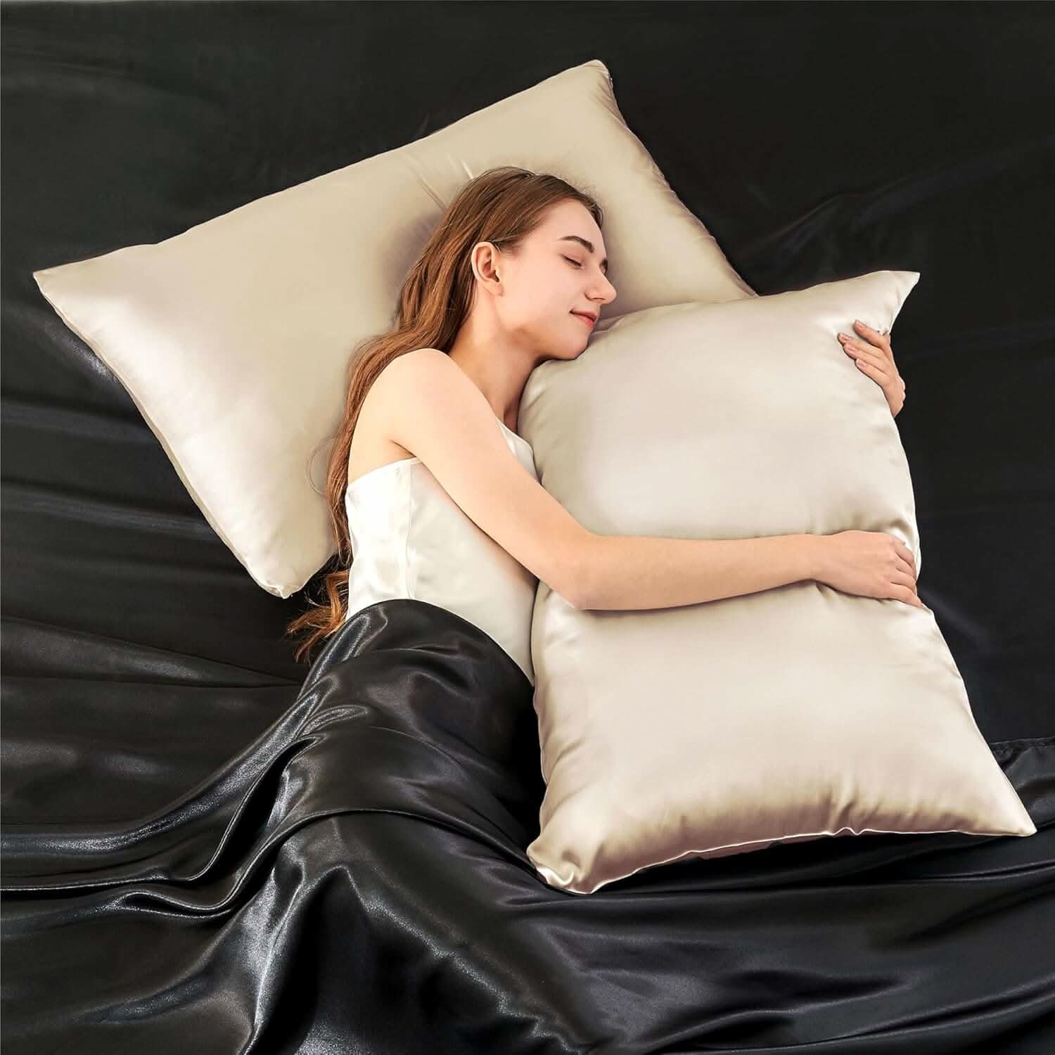 Woman lying on a bed hugging a champagne-colored silk pillowcase, highlighting its smooth and luxurious texture.