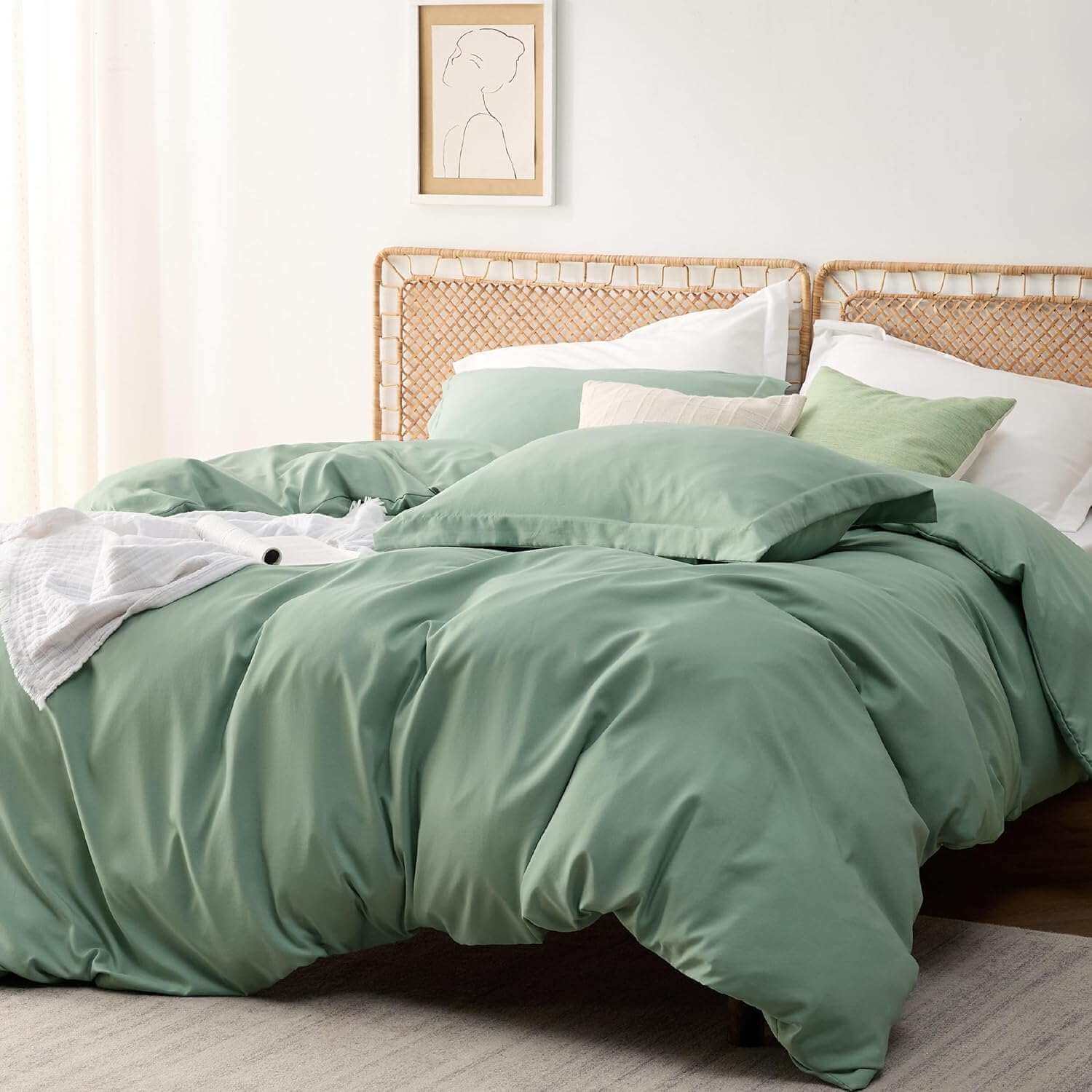 Sage green duvet cover set on a cozy bed with rattan headboard in a minimalist bedroom with natural light.