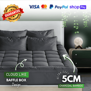 Luxury dark gray quilted mattress topper on a stylish bed, designed for enhanced comfort and support, with a modern bedroom setting in the background