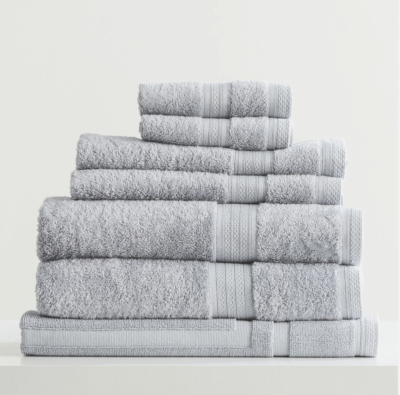 Stack of neatly folded gray towels on a white surface