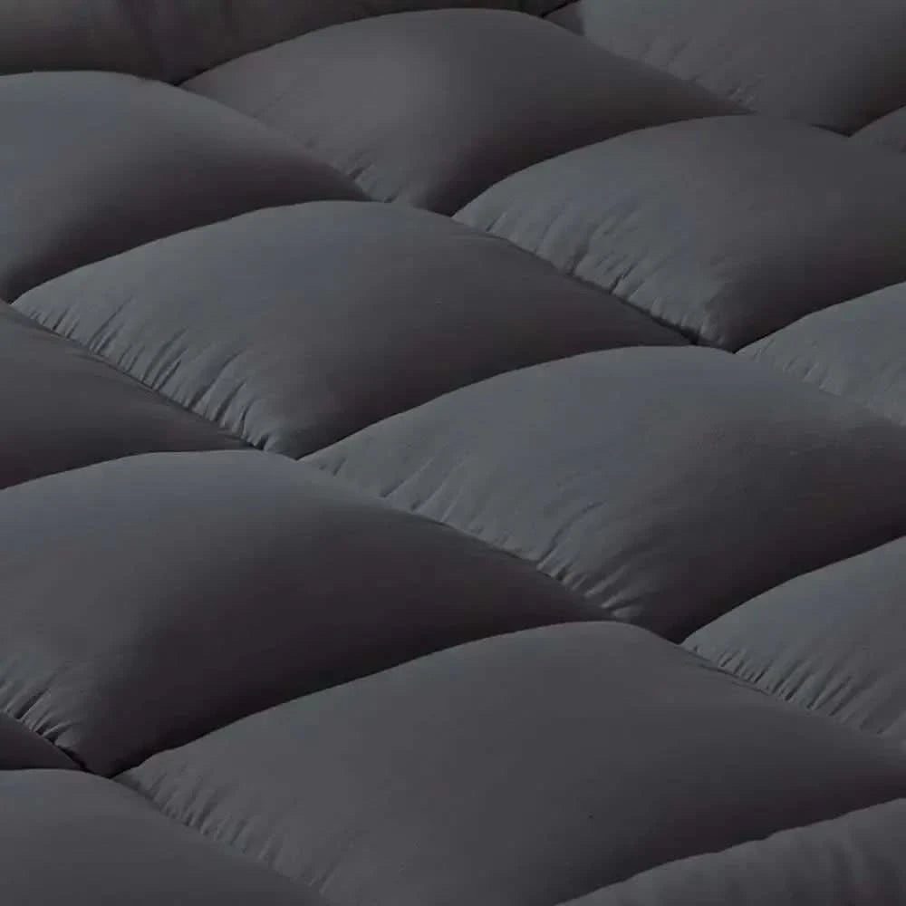 Close-up of a dark gray quilted mattress topper with a plush, padded design, showcasing its soft and cushioned texture.