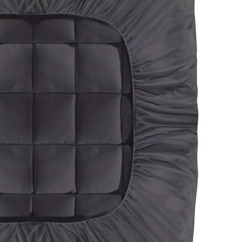 Close-up view of a dark gray quilted mattress topper with elasticized edges, ensuring a secure and snug fit on the mattress.